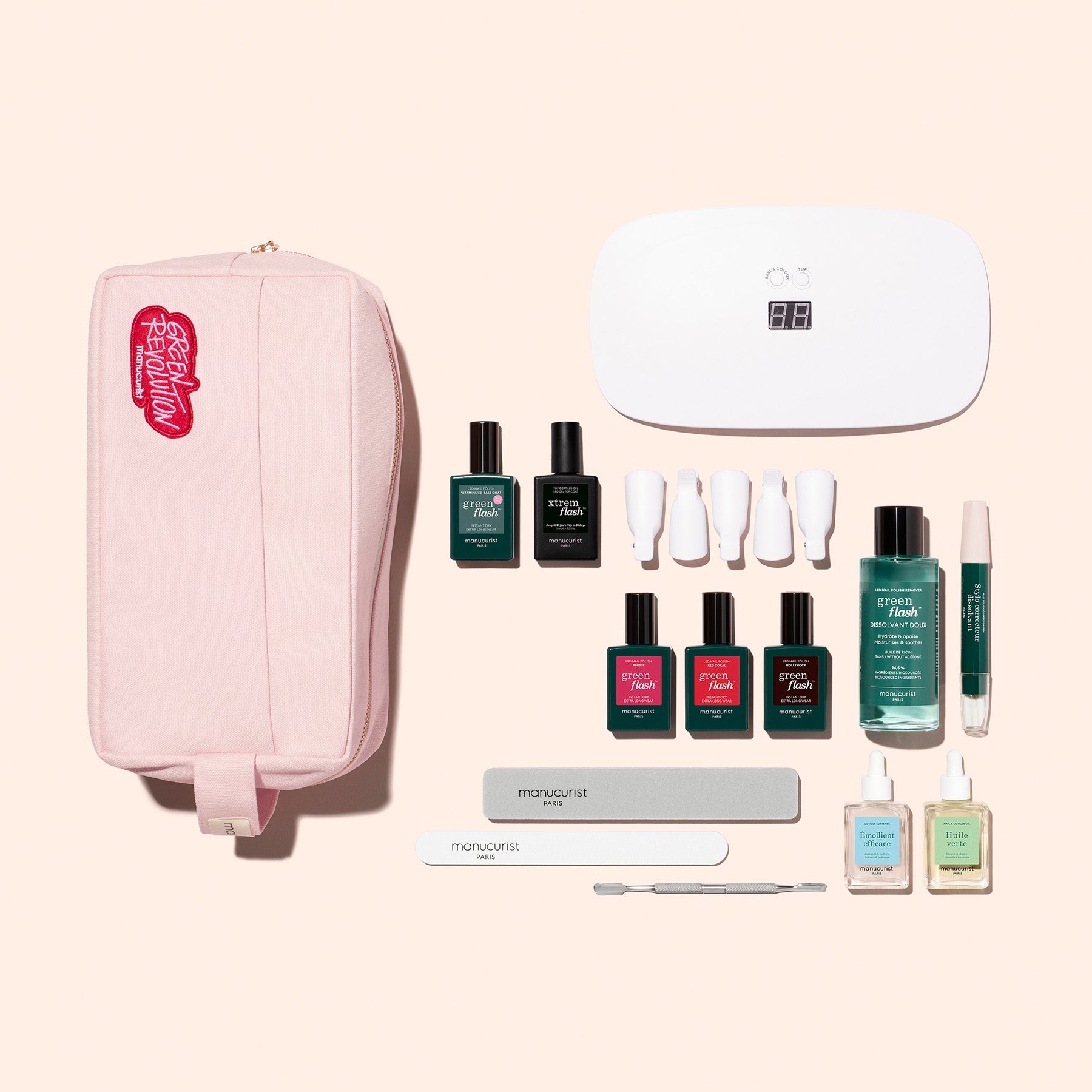 The Manucurist Ultimate Kit is displayed on a light beige background, featuring a pink pouch, manicure tools, gel polish bottles, nail care products, a Vitaminized Base Coat, nail files, a cuticle pusher, and a compact white LED lamp.