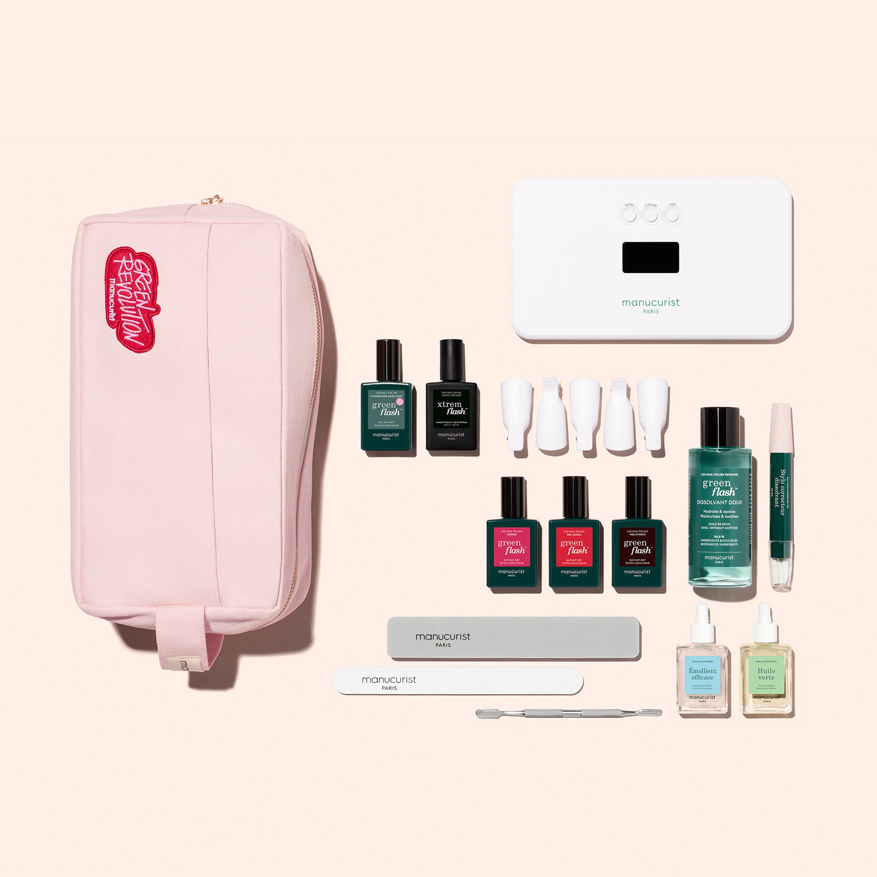 The Manucurist Ultimate Kit, featuring a pink zippered pouch, gel polish, white LED lamp, nail files, Vitaminized Base Coat, and more, provides everything needed for an ultra-glossy manicure—all arranged on a beige background.