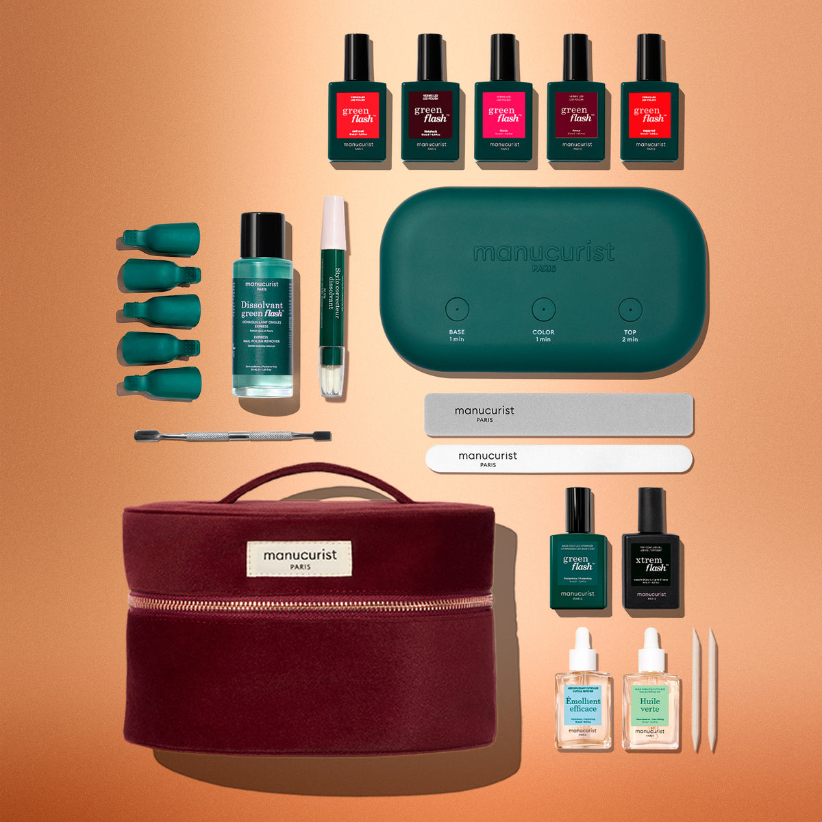 Le coffret kit super complet Green Flash™ de Manucurist comprend un vernis effet gel Green Flash™, des pinces de dépose, une lime, un bloc polissoir, un bâtonnet pour les cuticules, une lampe LED, une Base Coat, un Top Coat et une trousse de transport bordeaux, élégamment présentés sur un fond beige.