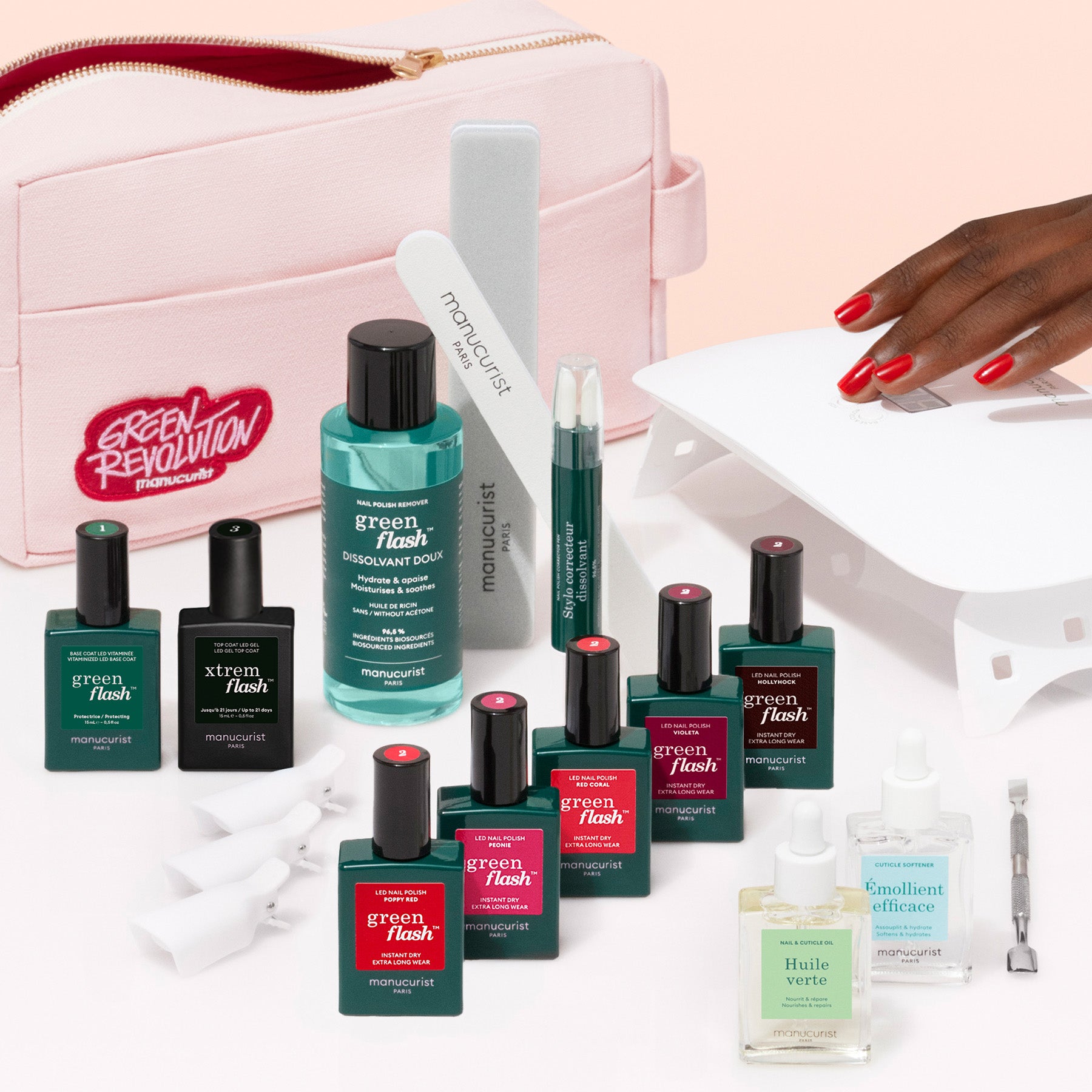The Manucurist Super Ultimate Kit features gel polish, remover, files, cuticle oil, and tools displayed before a pink pouch, with a hand showing glossy red nails and a white UV lamp for the perfect manicure.