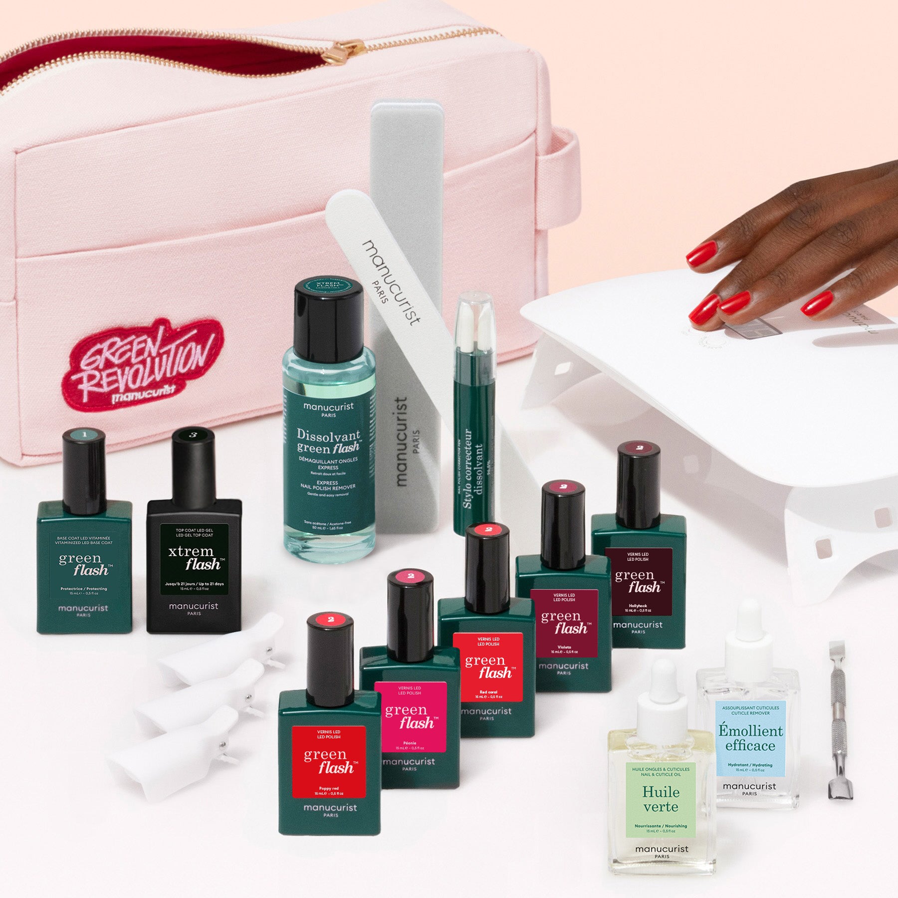 The Manucurist Super Ultimate Kit, featuring Green Flash gel polish, remover, nail oils, files, and a vitamin-enriched base coat with a pink bag. A hand with red nails showcases an ultra-glossy look under a white LED lamp.