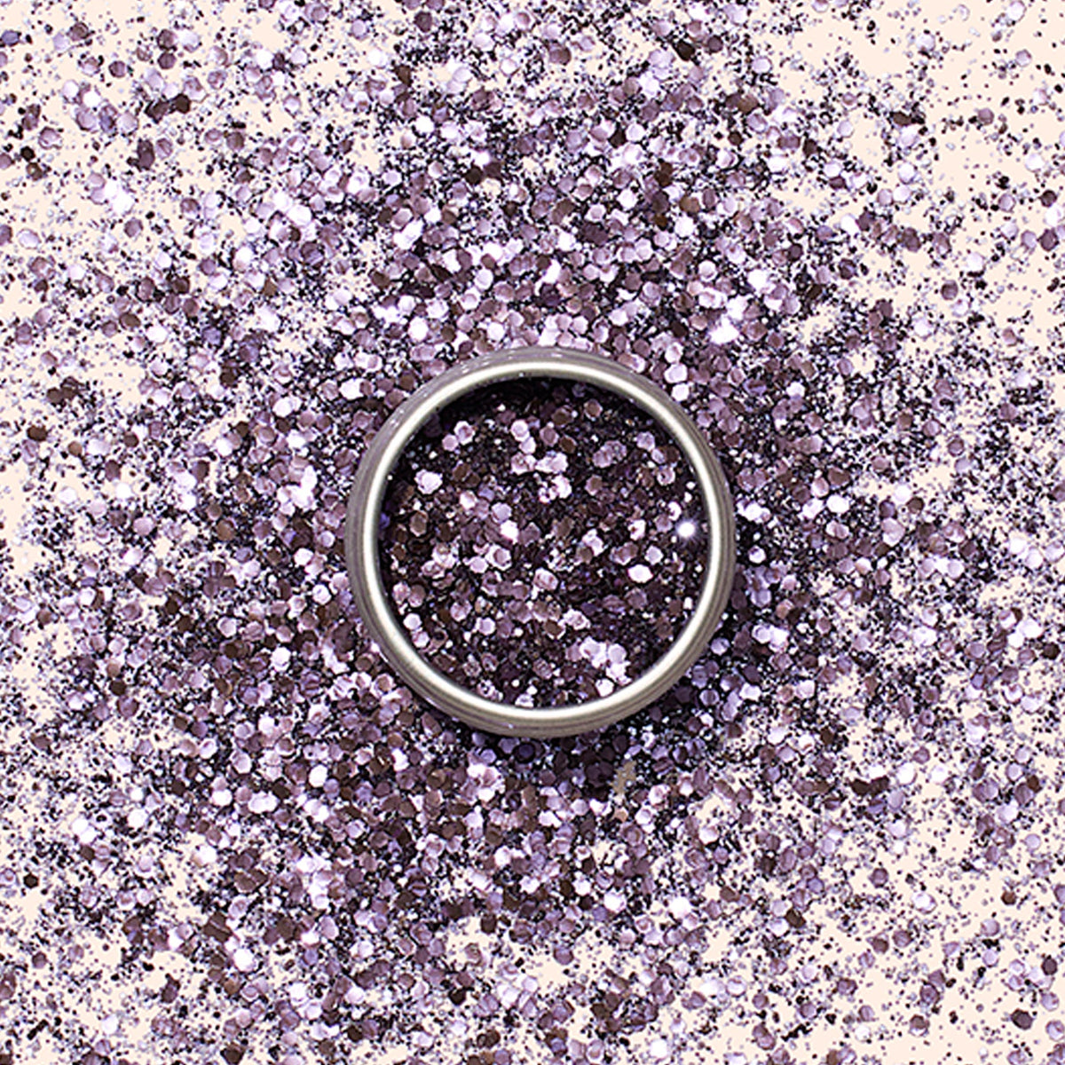 Une bague en argent repose sur une surface saupoudrée de Paillettes Biodégradables Manucurist, créant un fond scintillant et éco-responsable qui rappelle les créations de Nail Art.