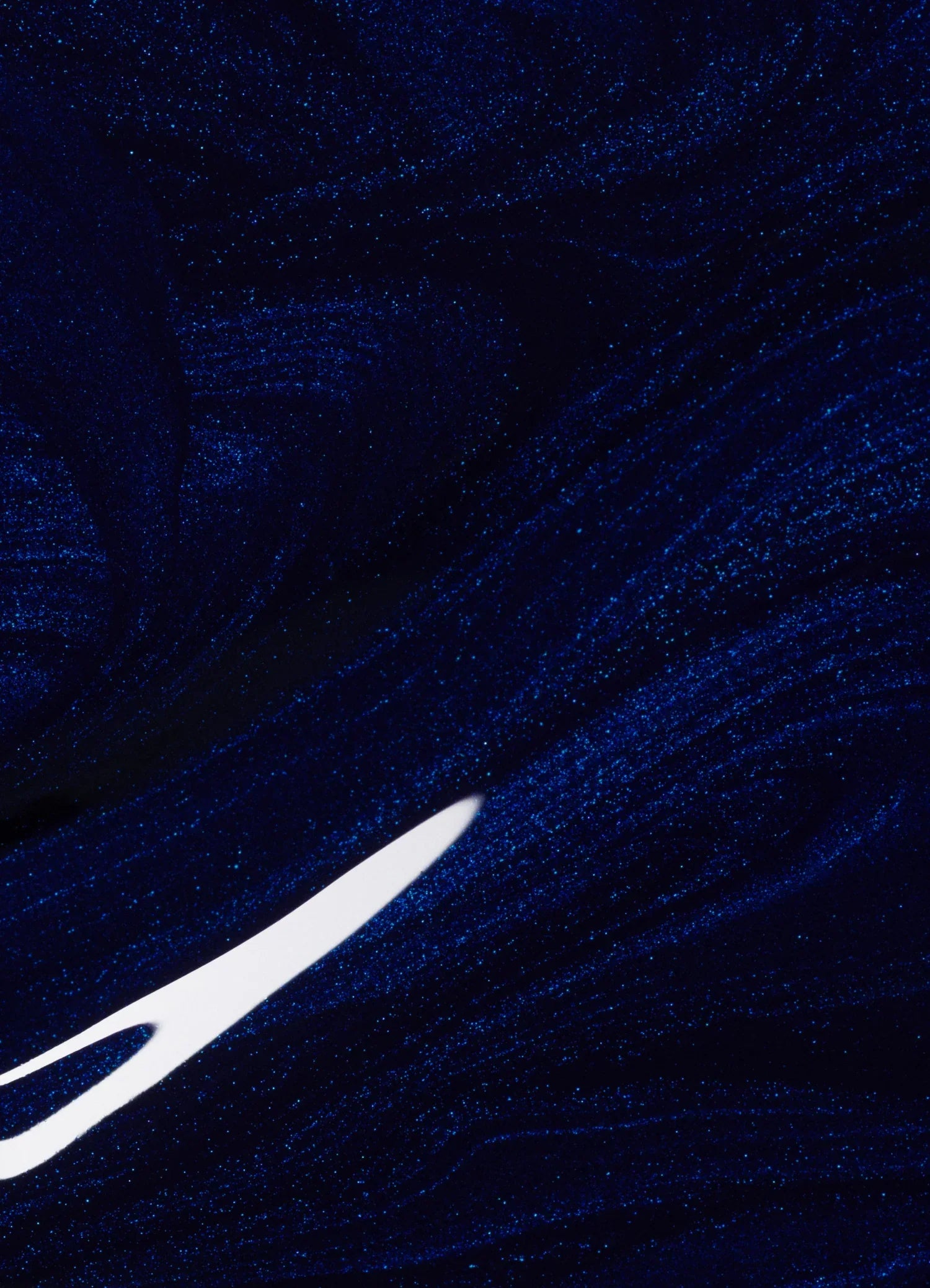 An abstract image featuring swirling, glittery dark blue patterns with a bright white, pointed streak cutting through the lower left area.