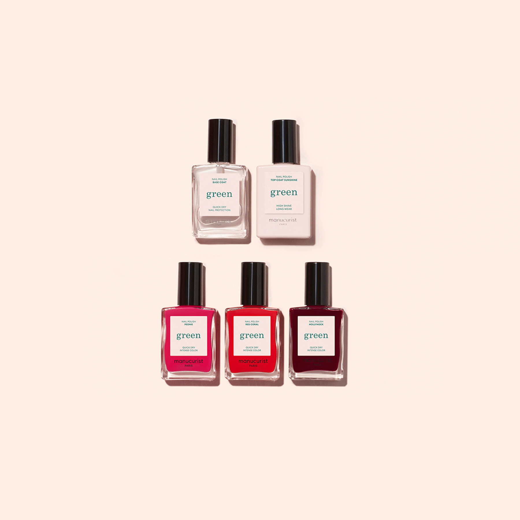 Five nail polish bottles from the Welcome kit Green by Manucurist-test are arranged in two rows on a beige background: two clear bottles above three in pink and red shades.