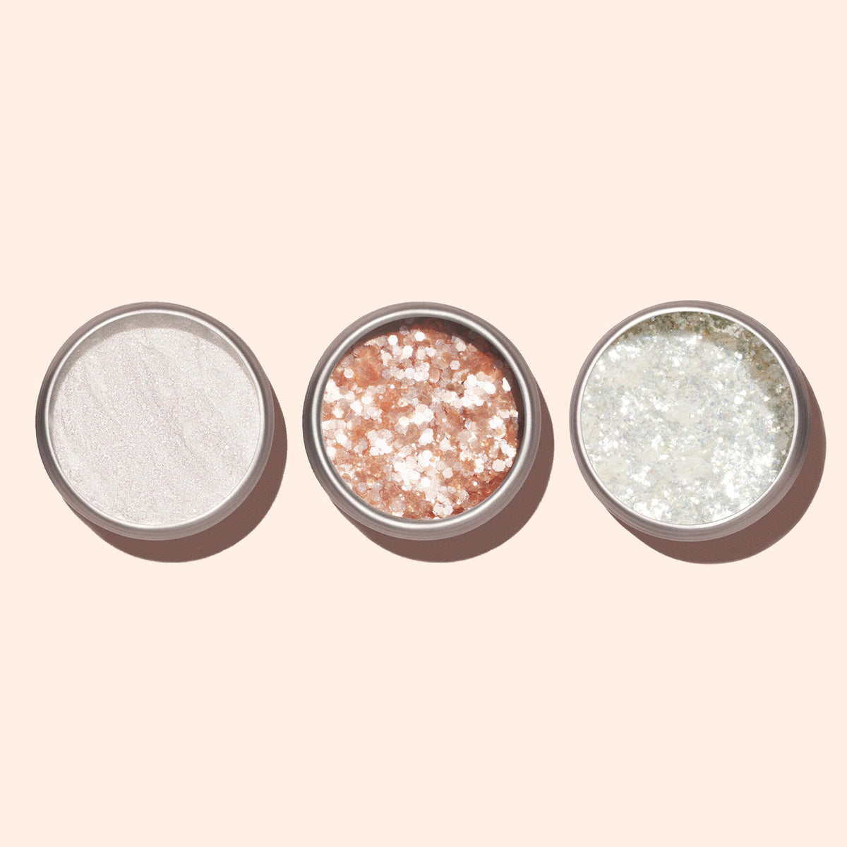 Trois pots ronds de Blush Biodegradable Glitter Manucurist — blanc, rose pâle avec de grosses paillettes pour le Nail Art, et argenté avec de fines paillettes écoresponsables — sont disposés côte à côte sur un fond pâle.