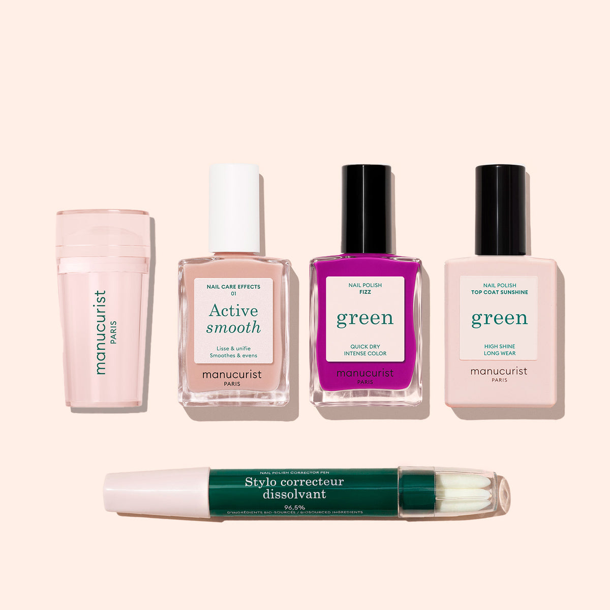 Le French Color Kit Manucurist, comprenant un émollient pour cuticules, un flacon de soin pour les ongles, des vernis rose vif et rose pâle étiquetés Green, et un stylo correcteur double embout, est présenté sur un fond beige clair.