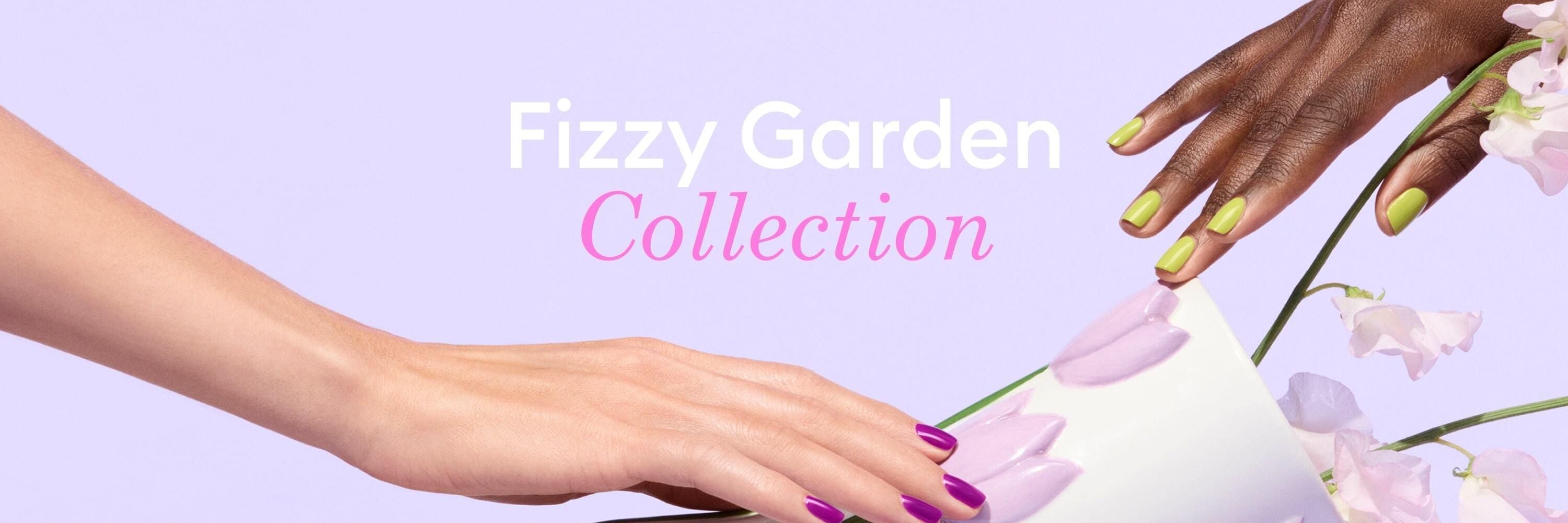 Two hands with colorful manicured nails reach toward a tipped-over white vase spilling pastel purple petals, with the text Fizzy Garden Collection on a light lavender background.