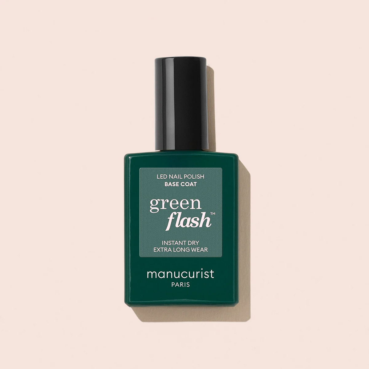 A bottle of Manucurist Green Flash™ Base Coat with a dark green label and black cap is shown against a light beige background.