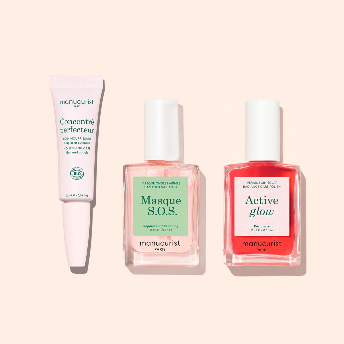 Le trio de soins pour les ongles Strong Glow de Manucurist est présenté sur un fond rose clair : un tube de Concentré Perfecteur, un flacon de Masque S.O.S. pour ongles abîmés et un flacon de vernis Active Glow rouge.