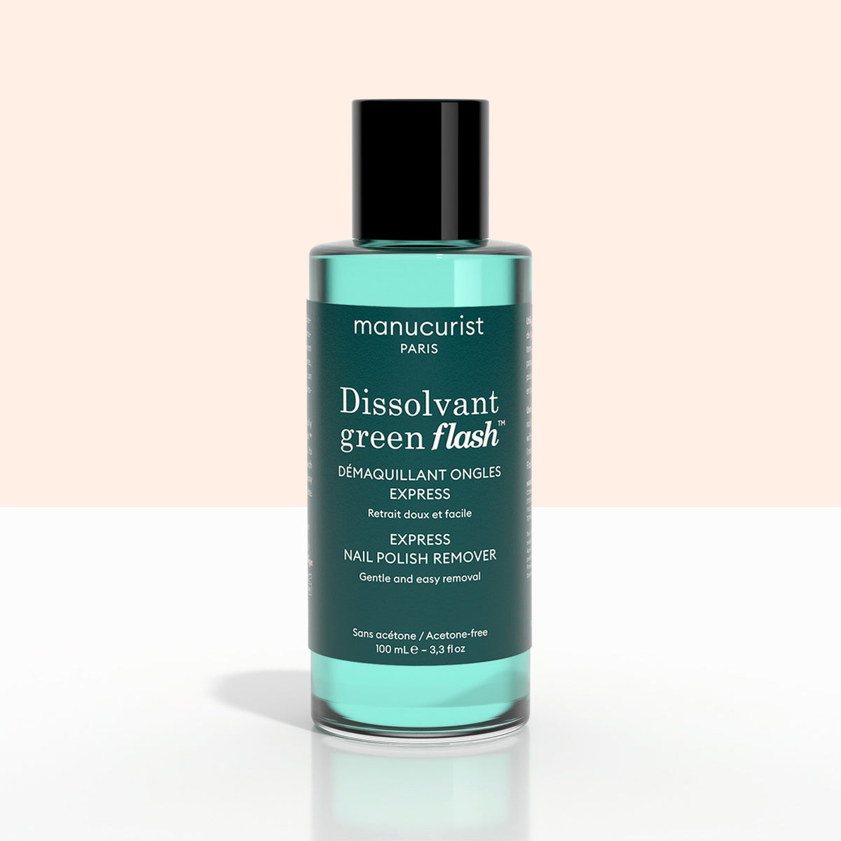 Un flacon vert de + Green Flash™ Gel Polish Remover de Manucurist-test, doux et sans acétone, composé à 99,4 % d’ingrédients biosourcés, posé sur une surface pâle devant un fond clair.
