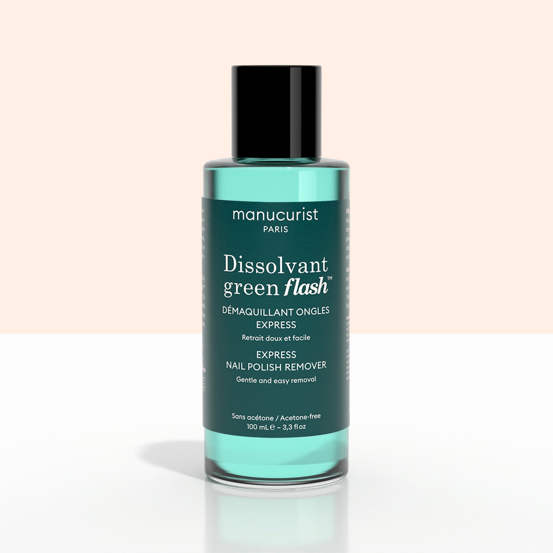 A green bottle of + Green Flash™ Gel Polish Remover by Manucurist-test, gentle and acetone-free with 99.4% bio-sourced ingredients, stands on a pale surface against a light background.