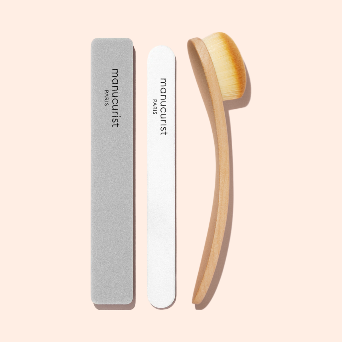 Trois accessoires de manucure sur un fond rose pâle : une lime à ongles grise, l&
