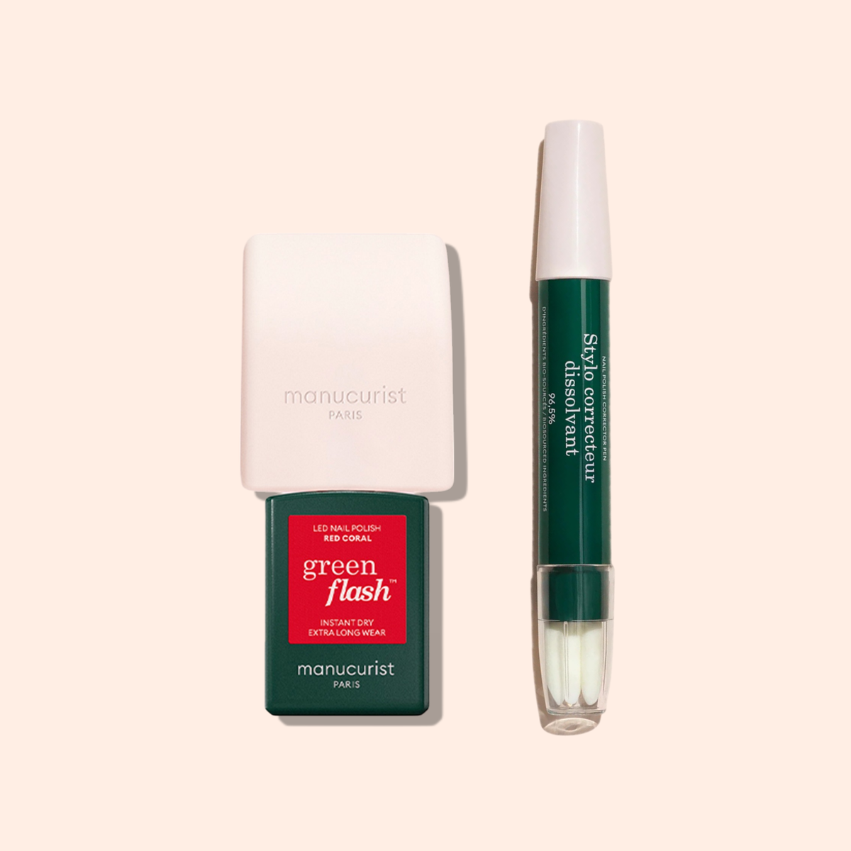 Two manicure products on a beige background: a green and white Manucurist US nail polish bottle in red coral, and the Manucurist US Mani Helper, a double-ended slip corrector pen for flawless manicures and precise nail polish application.