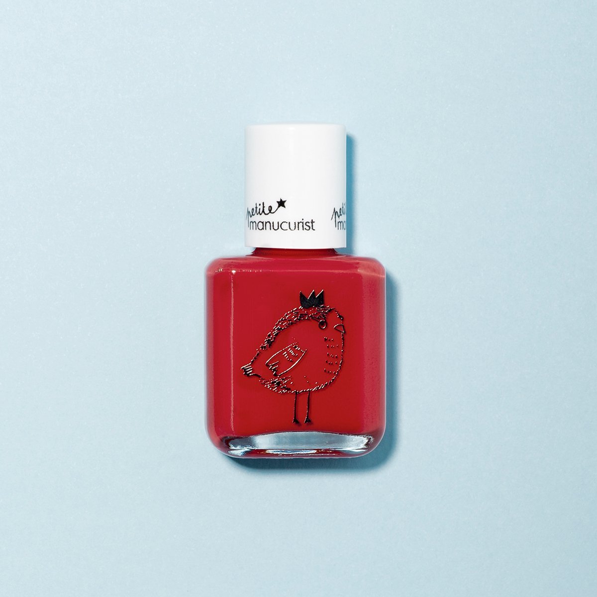 Un flacon de vernis à ongles pour enfants Manucurist, "Lucette la Fauvette," avec un capuchon blanc et un adorable dessin d’oiseau couronné sur le devant. Fabriqué à partir d’ingrédients d’origine naturelle, il ressort sur le fond bleu clair.