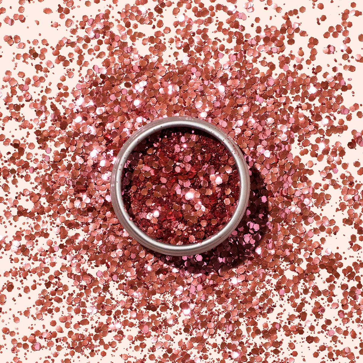 Un pot rond de paillettes biodégradables Manucurist, rempli de paillettes roses brillantes, est posé sur une surface parsemée d’éclats roses, créant un look festif et écoresponsable idéal pour le nail art.