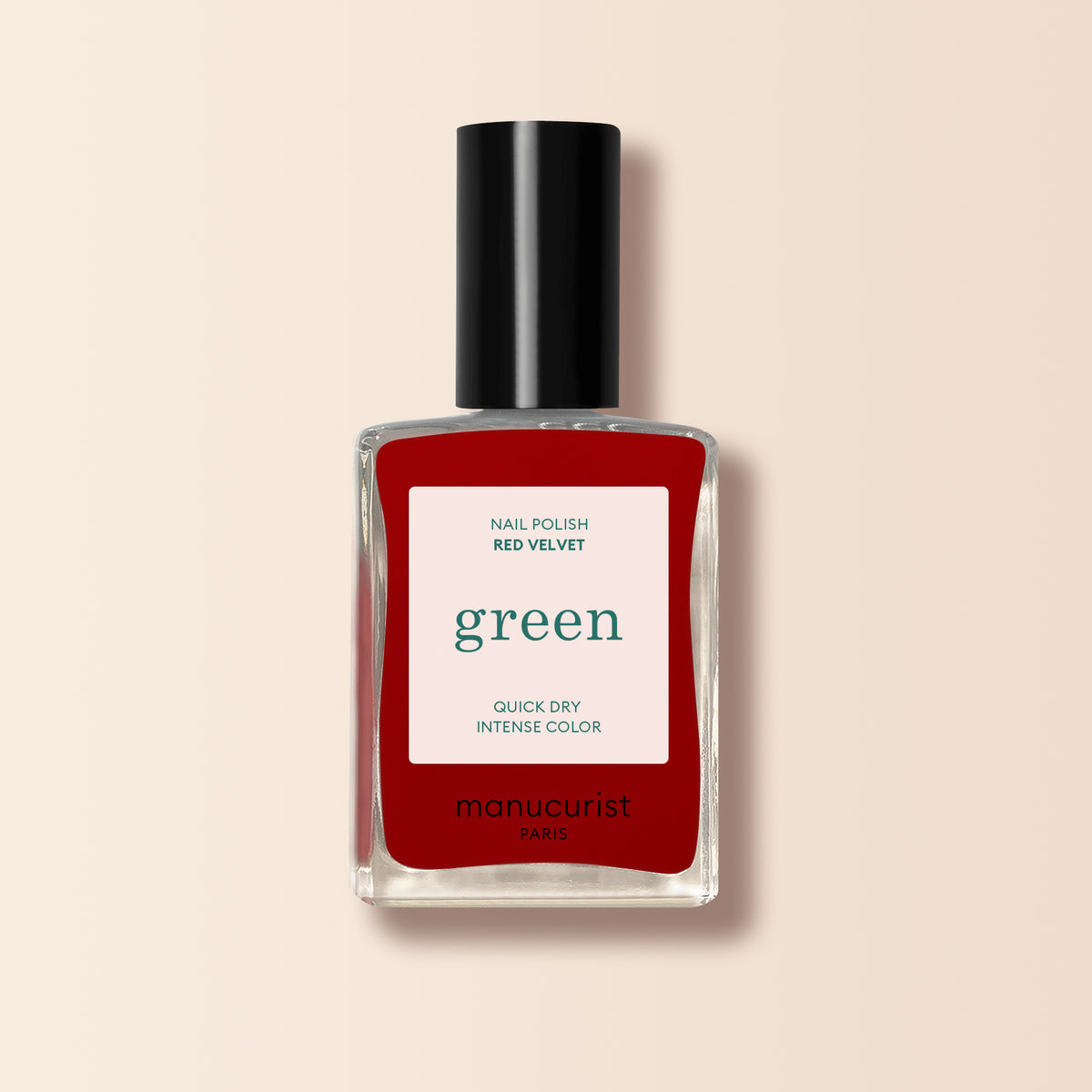 Un flacon de vernis à ongles Red Velvet de Manucurist de la gamme Green, avec un bouchon noir et une étiquette blanche "green", se détache sur un fond beige clair.