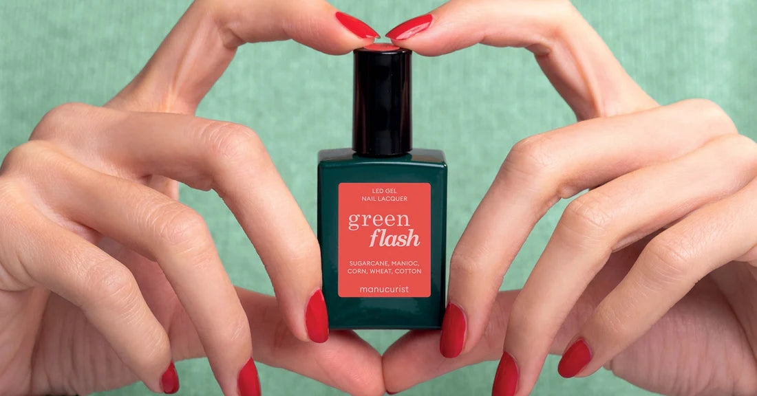 A person with red-painted nails holds a bottle of green flash LED gel nail lacquer against a green background, forming a heart shape with their fingers around the bottle.