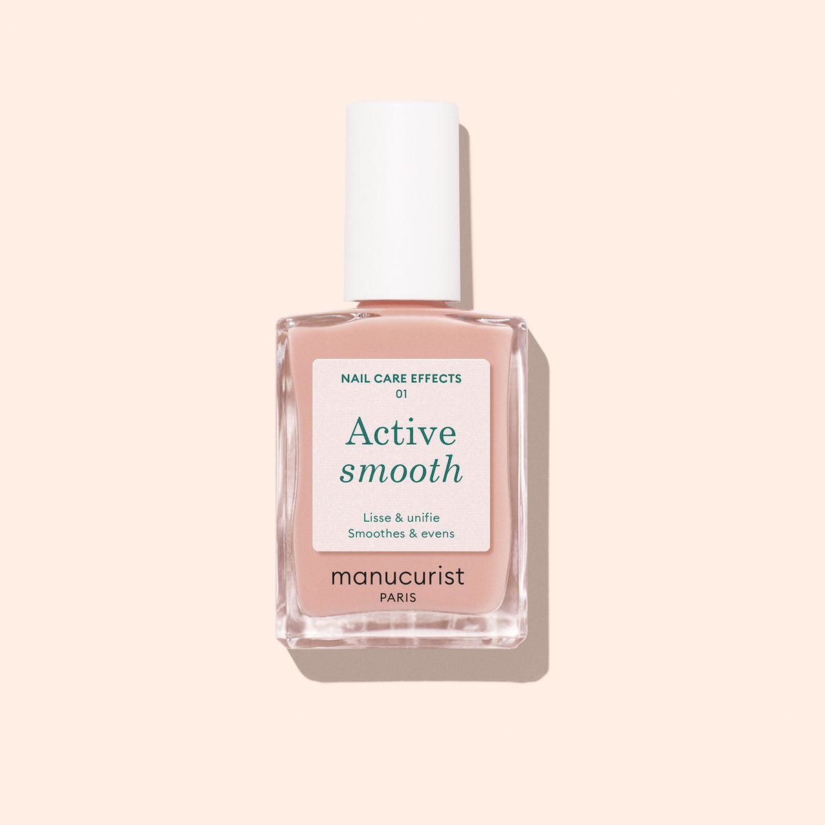 Un flacon de vernis soin Manucurist Active™ Smooth 01 avec un bouchon blanc est présenté sur un fond pêche pâle, mettant en valeur ce soin CC Polish d’origine végétale formulé pour perfectionner et protéger vos ongles.