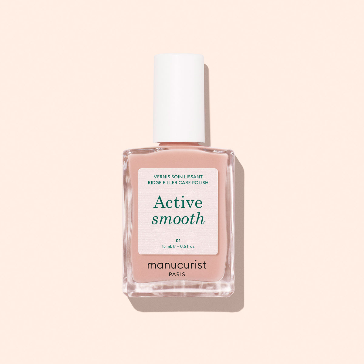 Un flacon de vernis soin Manucurist Active™ Smooth 01 avec un bouchon blanc est présenté sur un fond pêche pâle, mettant en valeur ce soin CC Polish d’origine végétale formulé pour perfectionner et protéger vos ongles.