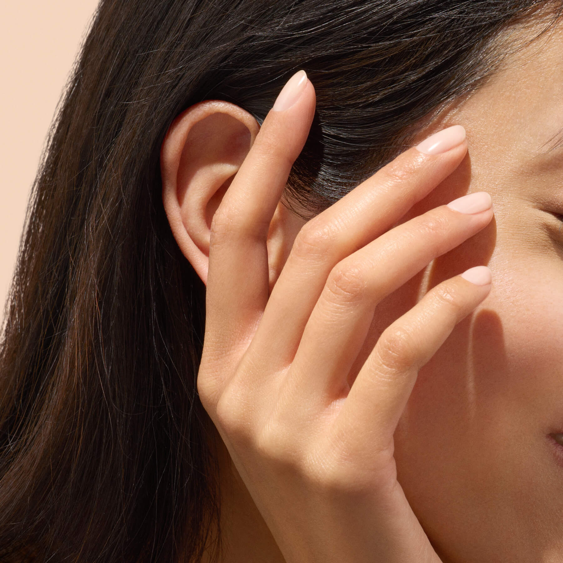 Hand with natural, healthy nails near face