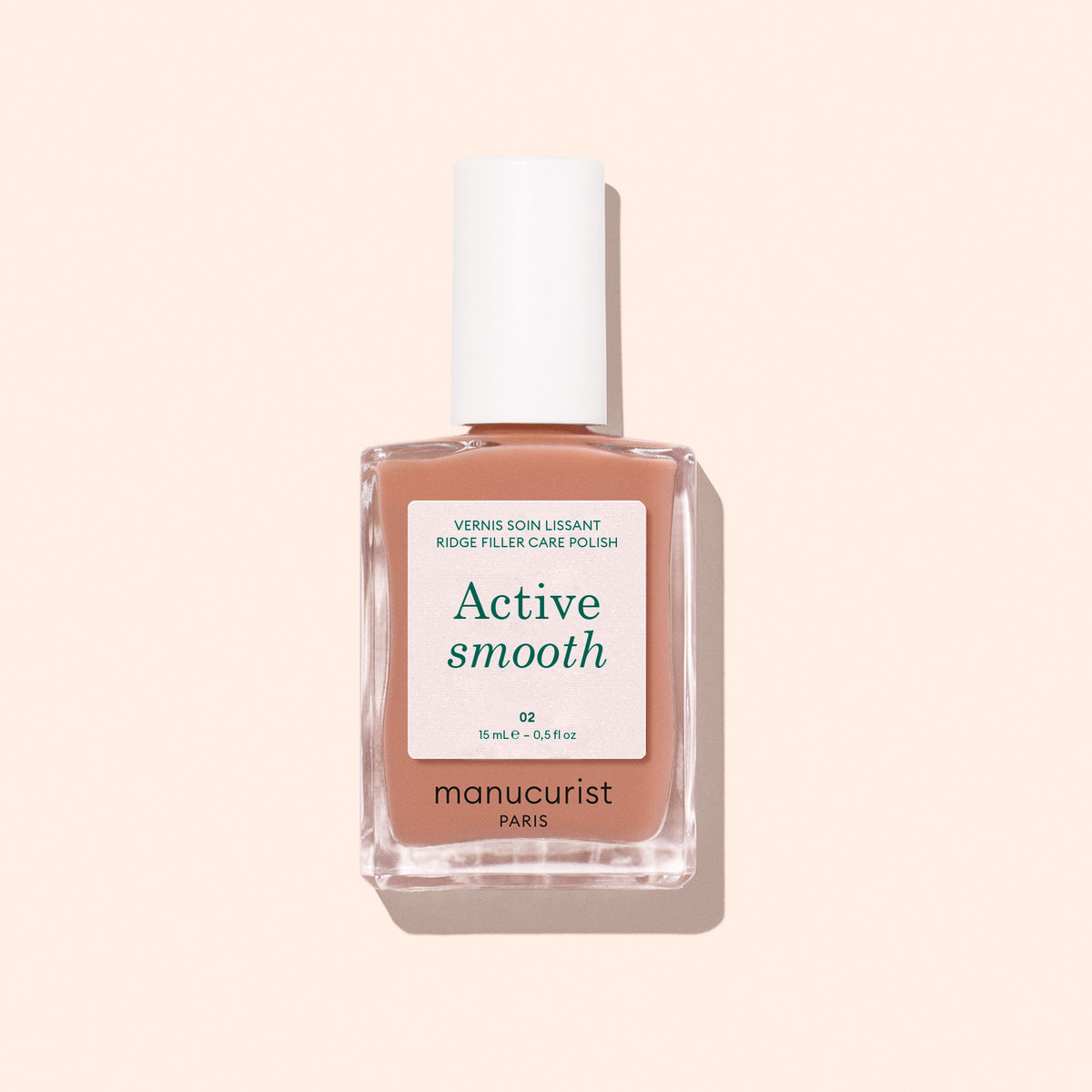 Un flacon de vernis soin Manucurist Active™ Smooth 02 au bouchon blanc, sur un fond pêche pâle. L&