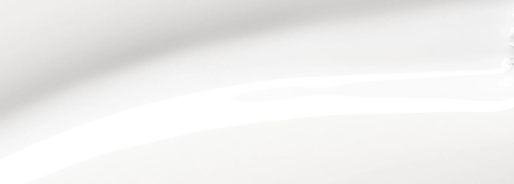 Close-up of a smooth, glossy white surface with subtle curves and highlights, suggesting ceramic or porcelain, possibly part of a plate or similar object.