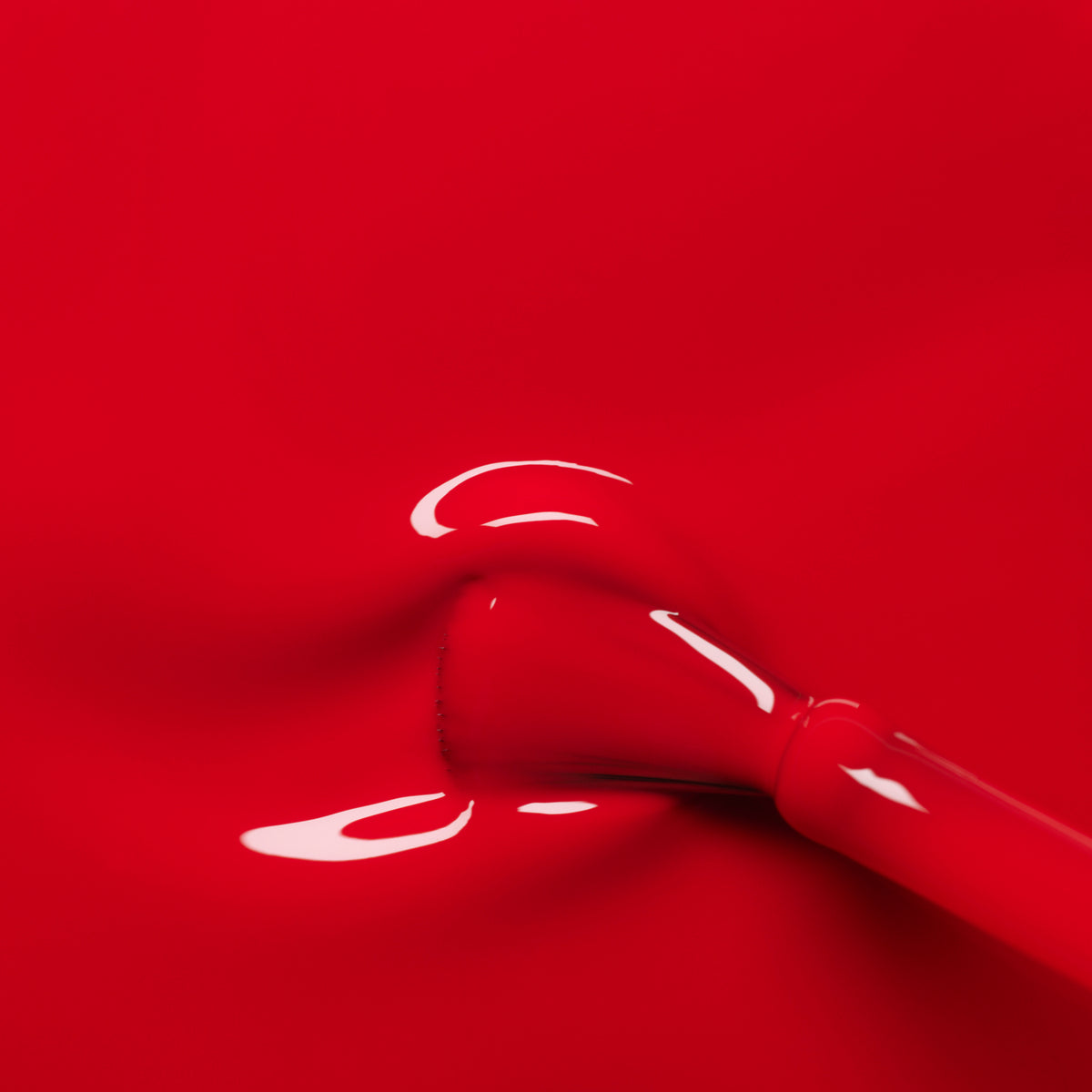 Gros plan sur l’application du vernis gel Poppy Red de Manucurist, révélant une couche lisse et brillante de rouge éclatant qui s’étale uniformément sur l’ongle.