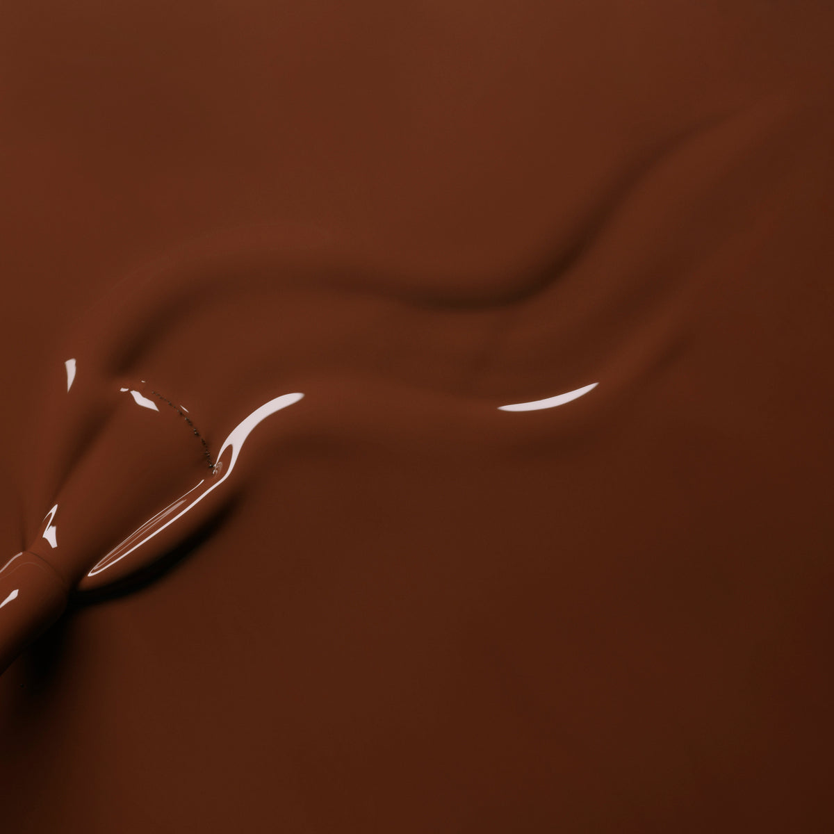 Close-up of smooth, melted chocolate in a warm brown hue being swirled, forming glossy waves that mirror the rich Chestnut shade of Manucurist&