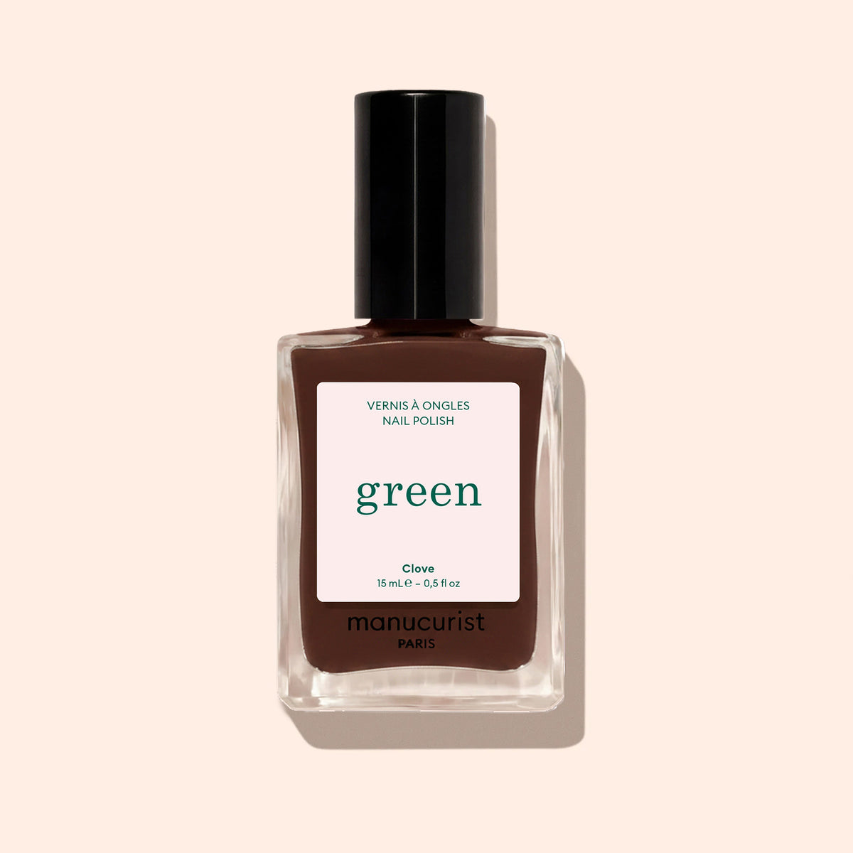 A bottle of Manucurist Clove nail polish, a chocolate brown shade from the Green™ range, features a black cap and a label reading "green, quick dry intense color" on a light beige background.