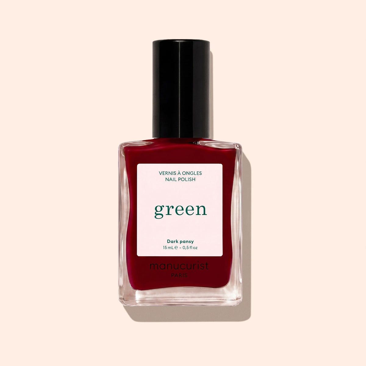 A bottle of Manucurist nail polish in the shade Dark Pansy, featuring a deep velvet red tone, black cap, and a Green™ range label on a beige background.