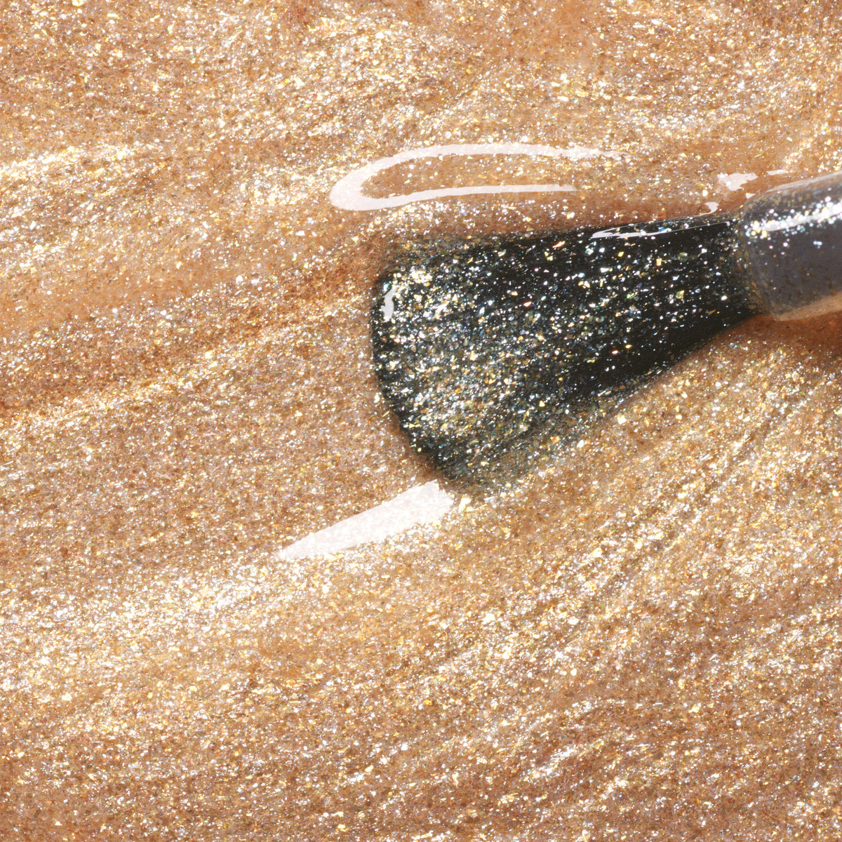 A close-up of a Manucurist Gold nail polish brush applying fine gold glitter for a sparkling, metallic effect from the Green range.