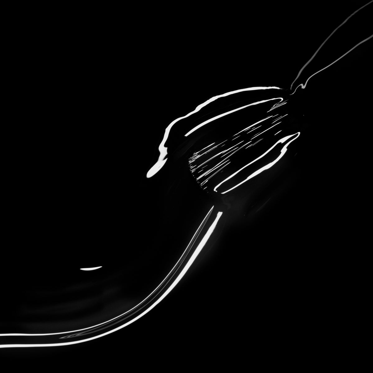 Une fourchette en métal brille avec Licorice de Manucurist, ses reflets chics noir vernis à ongles scintillant avec audace sur un fond noir profond.