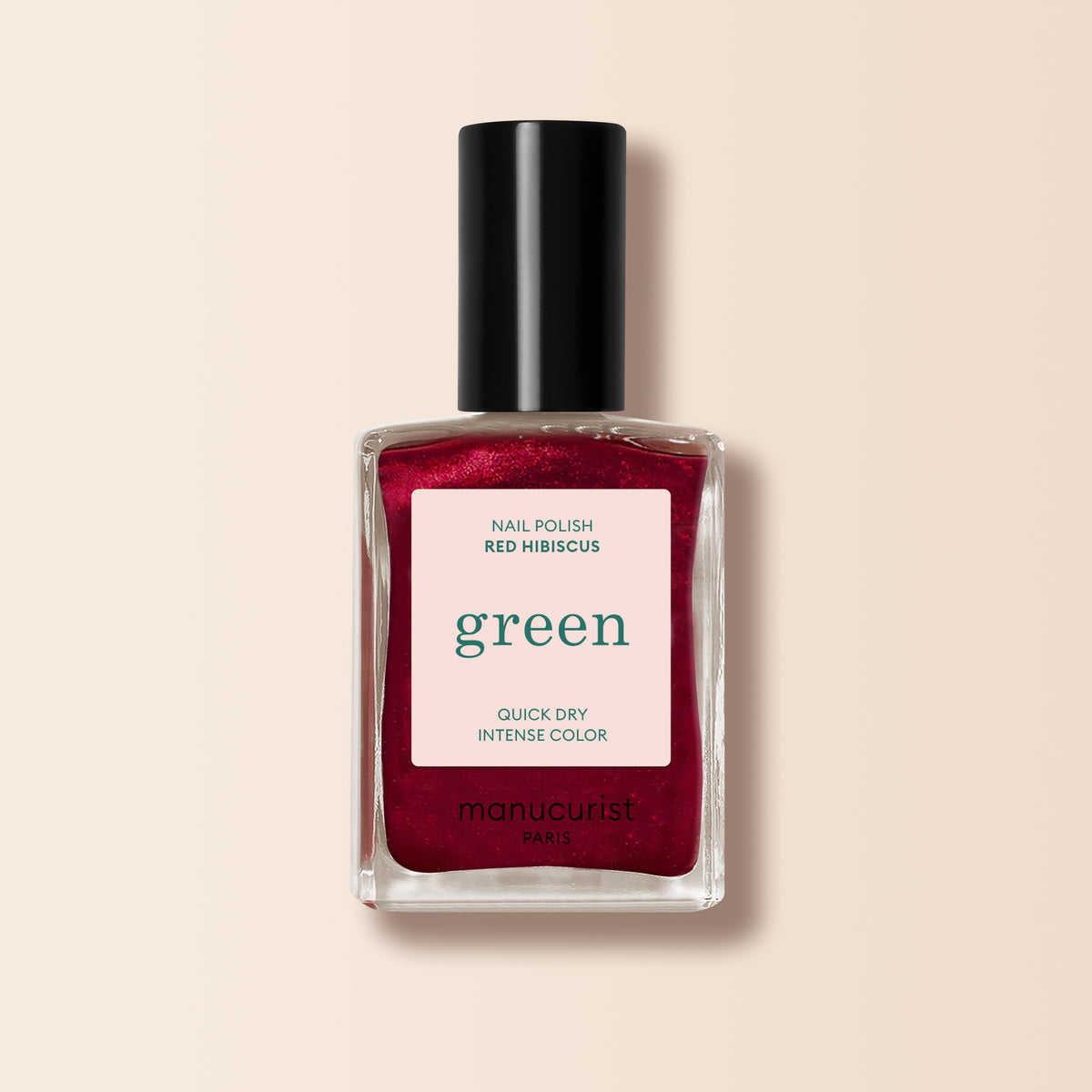 A clear glass bottle of Manucurist Red Hibiscus nail polish with a black cap and a label reading “Quick Dry Intense Color” is shown, featuring the product name on a light background.
