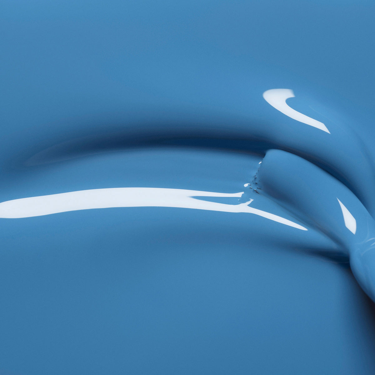 Close-up of glossy, smooth Manucurist Saphir paint with a thick, curved streak and reflective highlights, showing a jewel-toned, fluid texture.