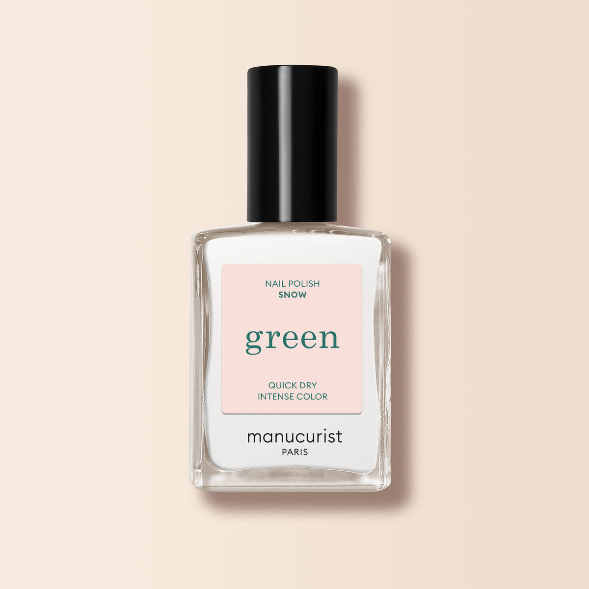 Un flacon en verre transparent de vernis à ongles Snow de Manucurist, avec un bouchon noir, étiqueté "Green." L’étiquette indique "Nail Polish Snow," et présente une couleur blanche pure, intense et à séchage rapide, sur un fond rose clair.