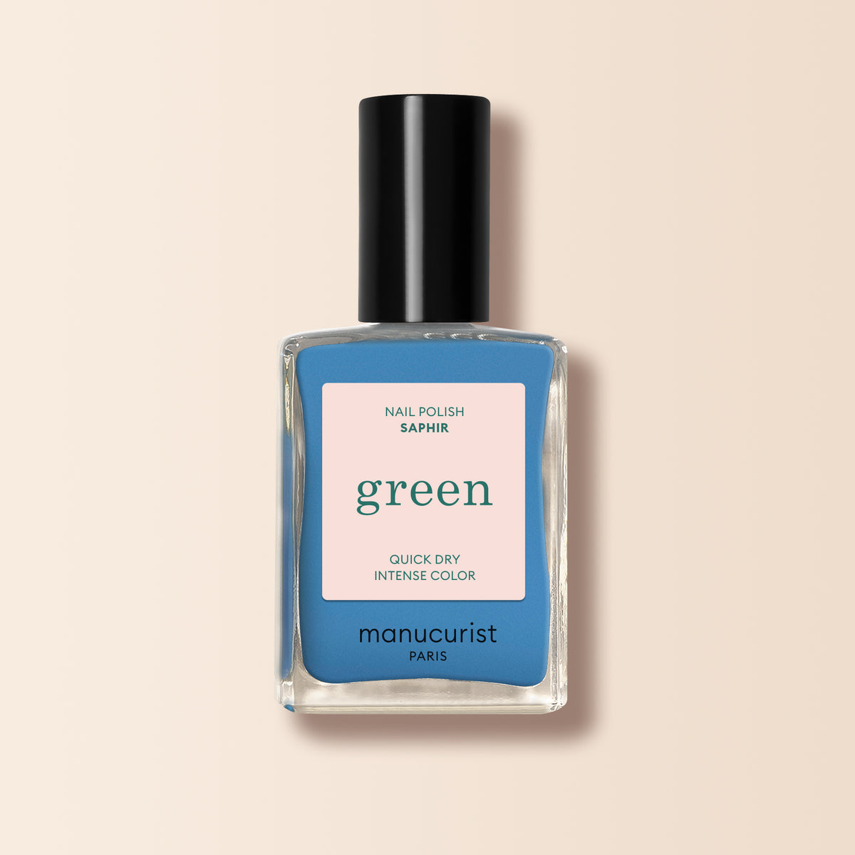 A bottle of Manucurist Saphir nail polish with a striking sapphire blue shade, a black cap, and a beige label featuring green and blue text.