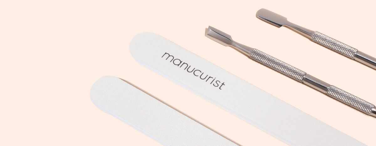A nail file labeled manucurist, a blue egg-shaped object with M7XQ, and two metal cuticle pushers on a light beige background.