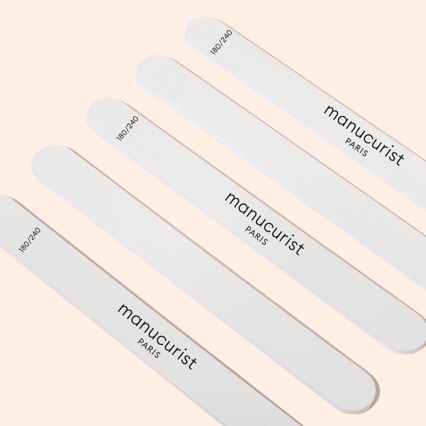 Five Manucurist-us 180/240 emery boards for fragile nails are arranged diagonally on a light beige background, ideal for gently shaping brittle or sensitive nails.