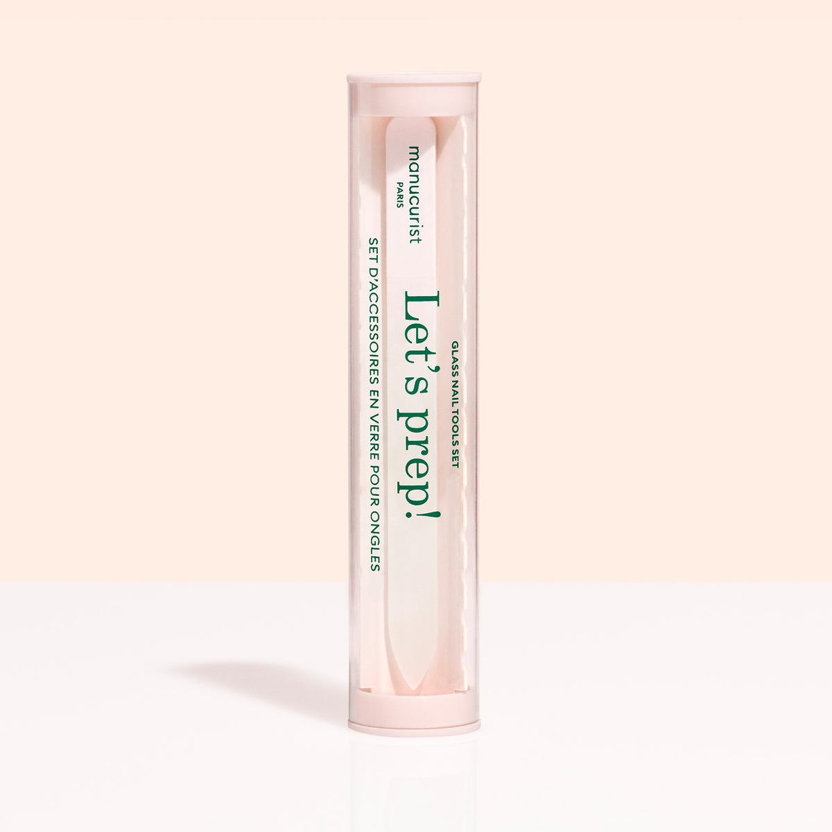 A cylindrical, clear container with a pink lid and base holds the Glass nail accessory trio by Manucurist-us. The label says "Lets prep!" and "manucurist Paris," with text in English and French.