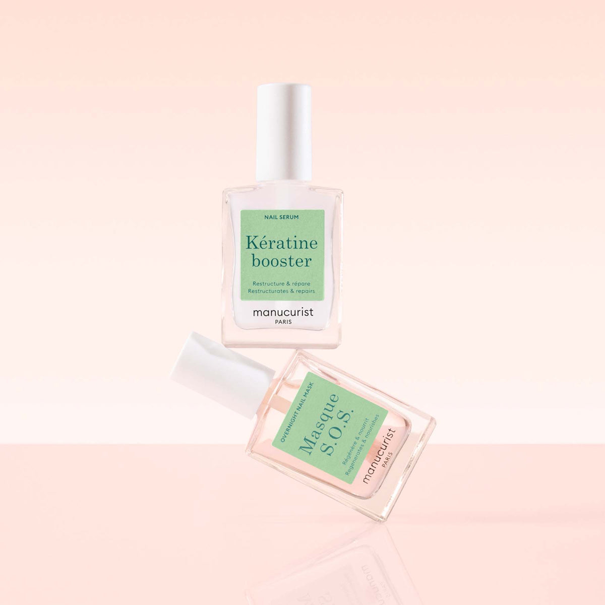 Deux flacons transparents de soin ongles Manucurist Day Night Duo avec des bouchons blancs sont posés sur un fond rose poudré. Le duo comprend un booster sérum à la kératine et un masque ongles Masque S.O.S, tous deux pour un traitement efficace des ongles.