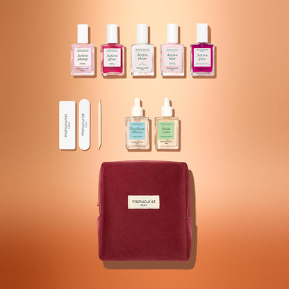 Le coffret cadeau Manucurist Active™ Starter Kit, avec cinq flacons de vernis à ongles, deux flacons en verre avec pipette, deux limes à ongles, un repousse-cuticules en bois et une pochette zippée, sur un fond dégradé.