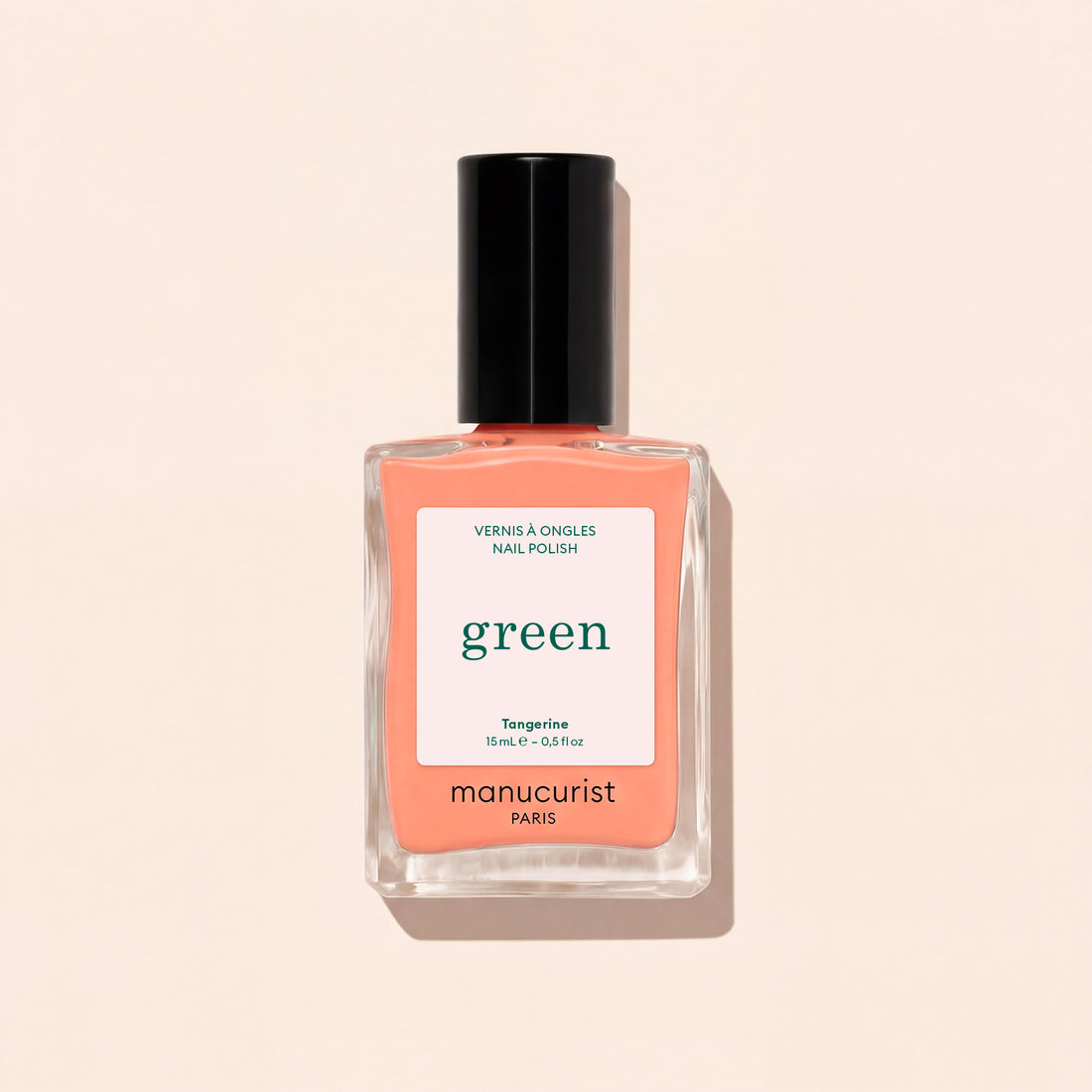 Manucurist Tangerine nail polish features a light orange shade with a black cap and white label with green and black text, shown against a light beige background. This vibrant color adds a lively pop to your look.