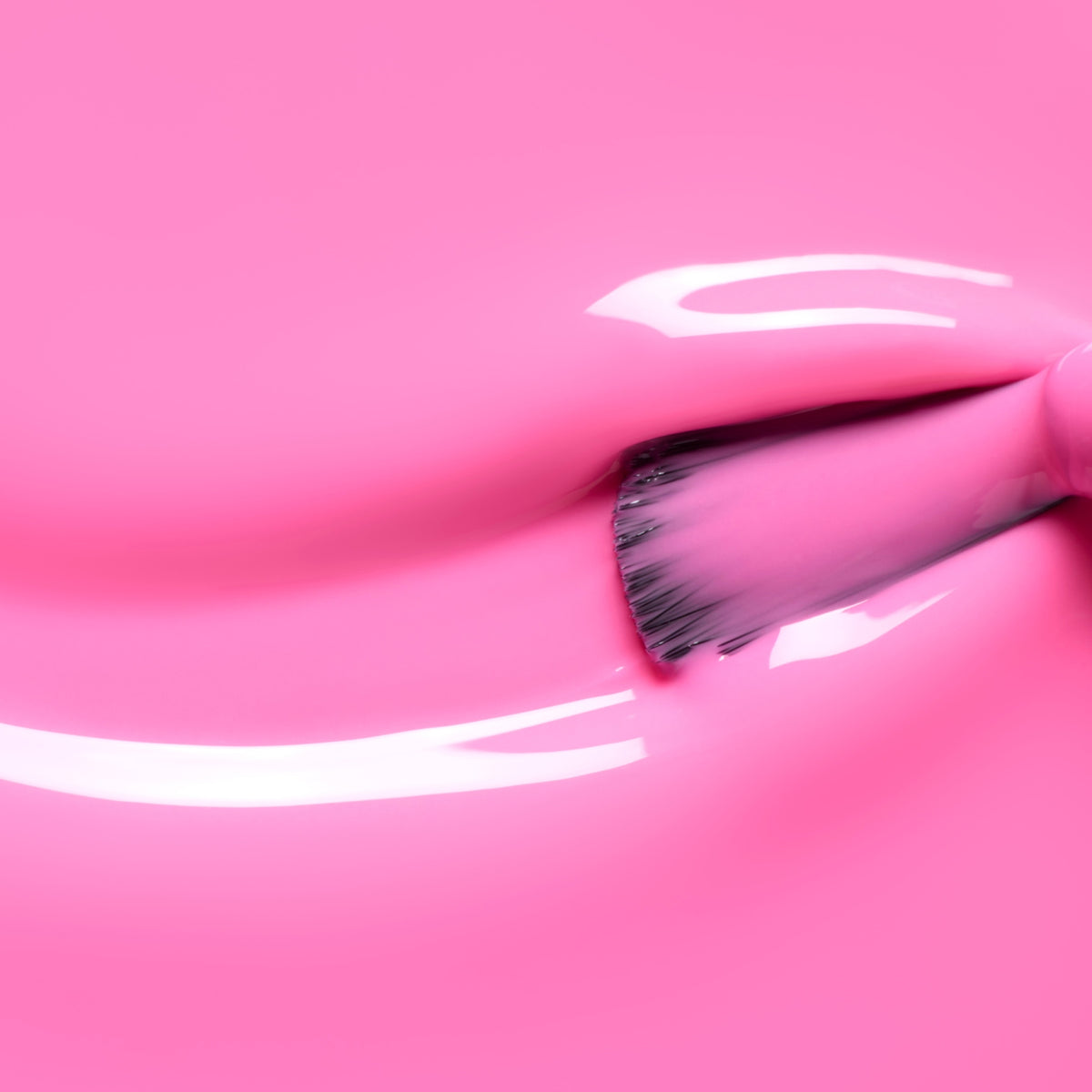 Gros plan sur un pinceau appliquant le vernis gel Bloom de Manucurist en rose néon, créant des traînées brillantes et réfléchissantes ainsi qu’une intensité magnétique sur une surface lisse.