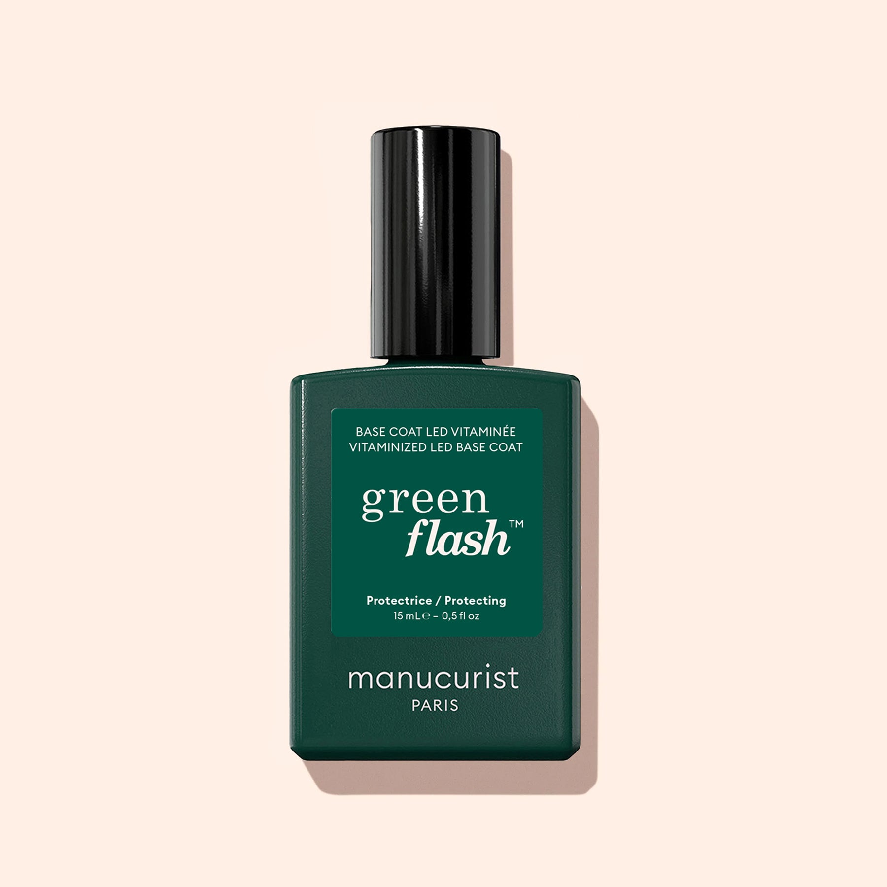 A dark green bottle of Manucurist Vitaminized Base Coat Green Flash™ with KeraHCE+ stands upright on a light beige background. The label displays white text and the Green Flash logo.