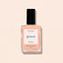 A bottle of Manucurist Milky Peach nail polish rests on a light beige surface. The clear bottle, featuring a black cap and a white label with green and peach lettering, beautifully highlights this soft peach shade from Manucurist.