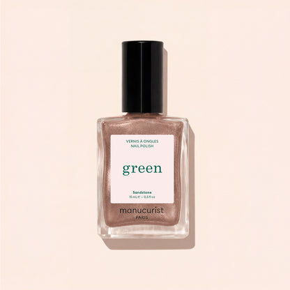 A bottle of Manucurist nail polish in the shade Sandstone, a shimmery rose gold hue, displayed against a light beige background.