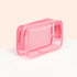 The Mini Jelly Bag by Manucurist is a small, rectangular, transparent pink bag with "manucurist PARIS" on the front—ideal for travel manicure kits or nail polish storage. Shown on a white surface with a pale peach backdrop.