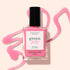 A bottle of Manucurist Pink Sorbet Jelly nail polish rests on a light beige surface, surrounded by translucent pink polish artistically spilled around it.