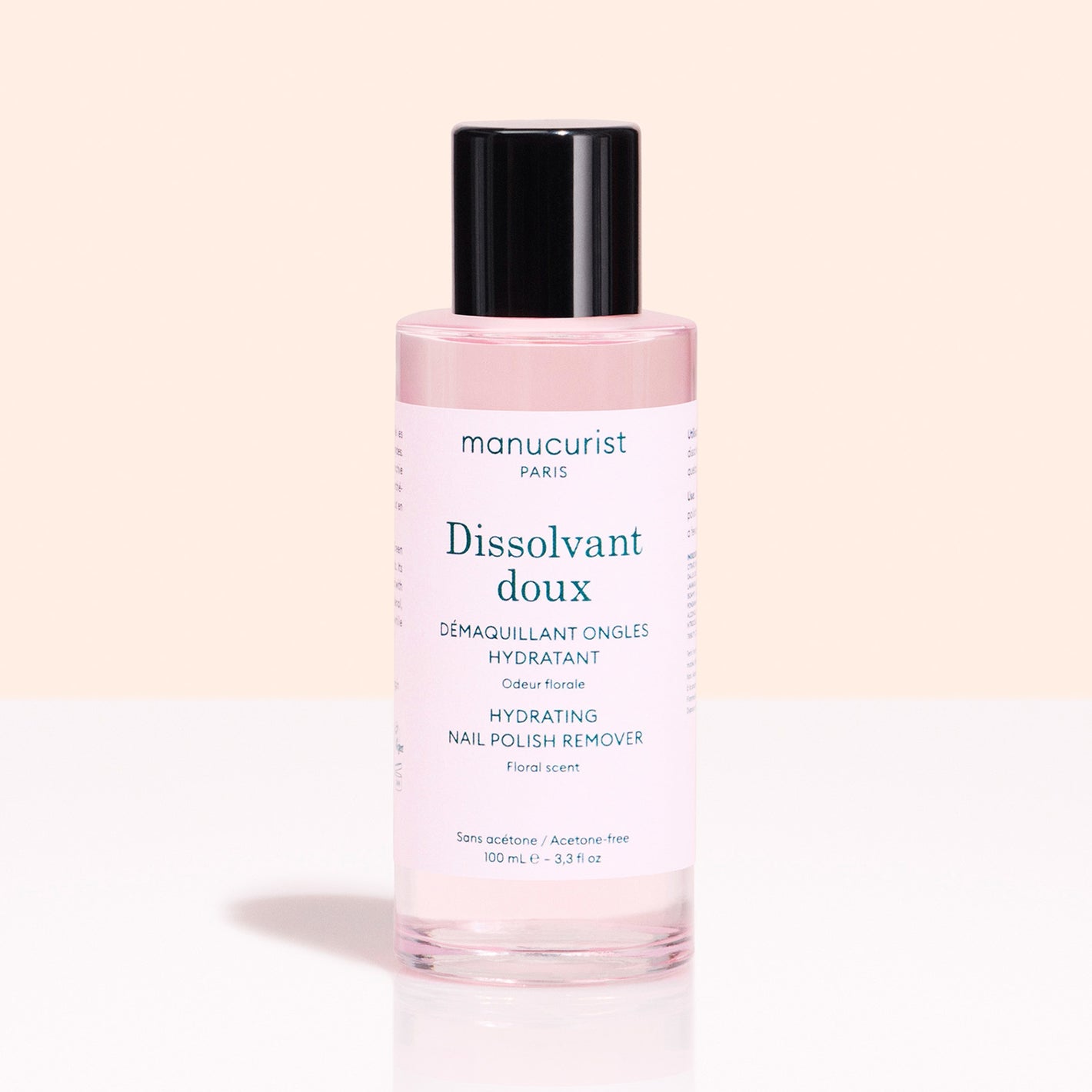 A pink bottle of Manucurist Gentle Remover with a black cap sits against a light pink background. The label notes it's acetone-free and floral scented.