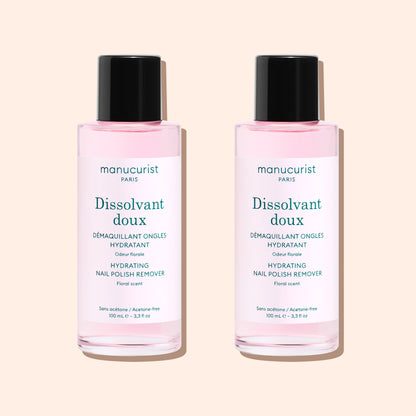 Two bottles of Manucurist Gentle Remover, featuring pale pink, acetone-free liquid with black caps and white labels, are placed side by side on a light beige background.